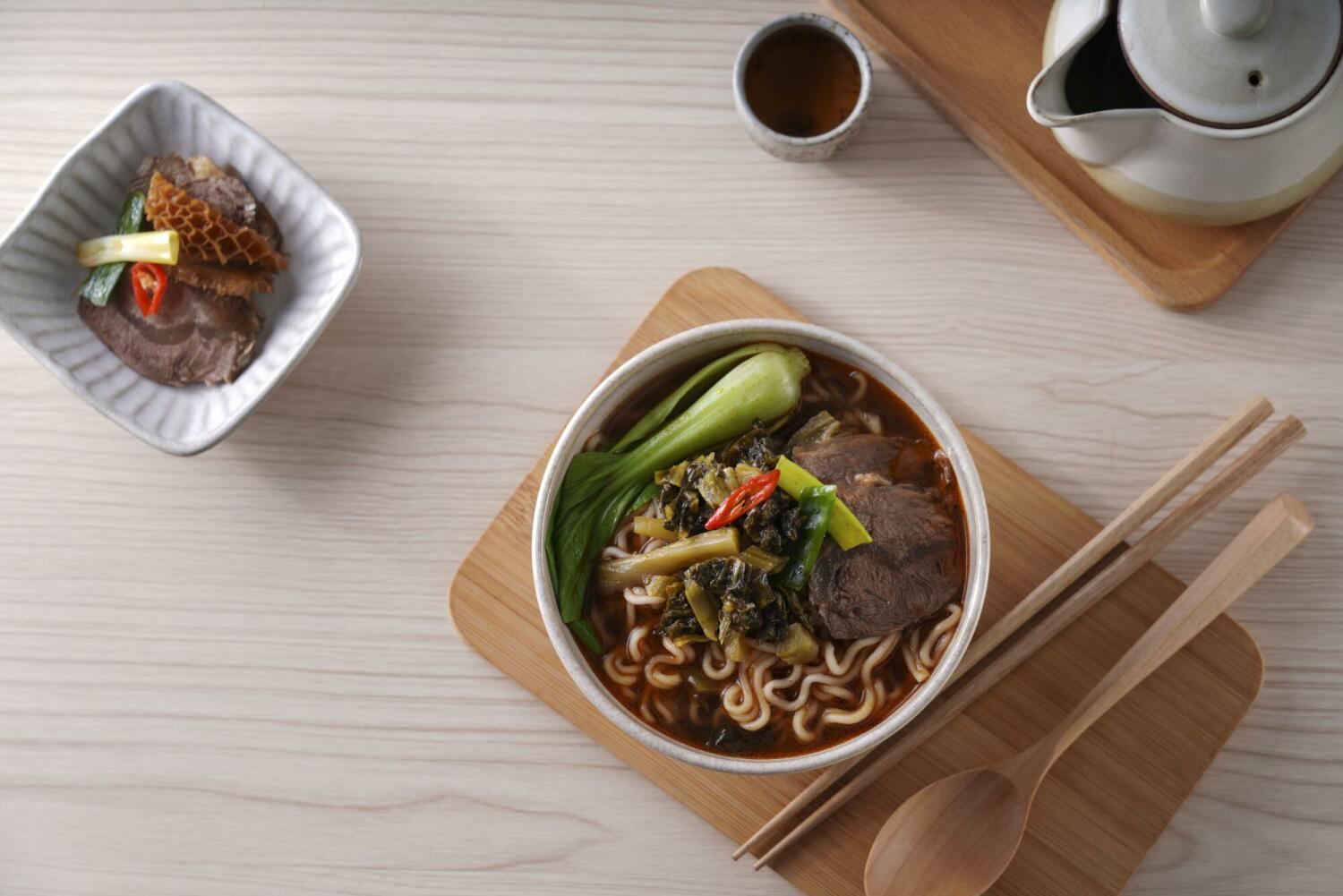 A comforting bowl of SING-LIN FOODS beef flavored ramen served with tender beef, bok choy, and a generous topping of pickled mustard greens.