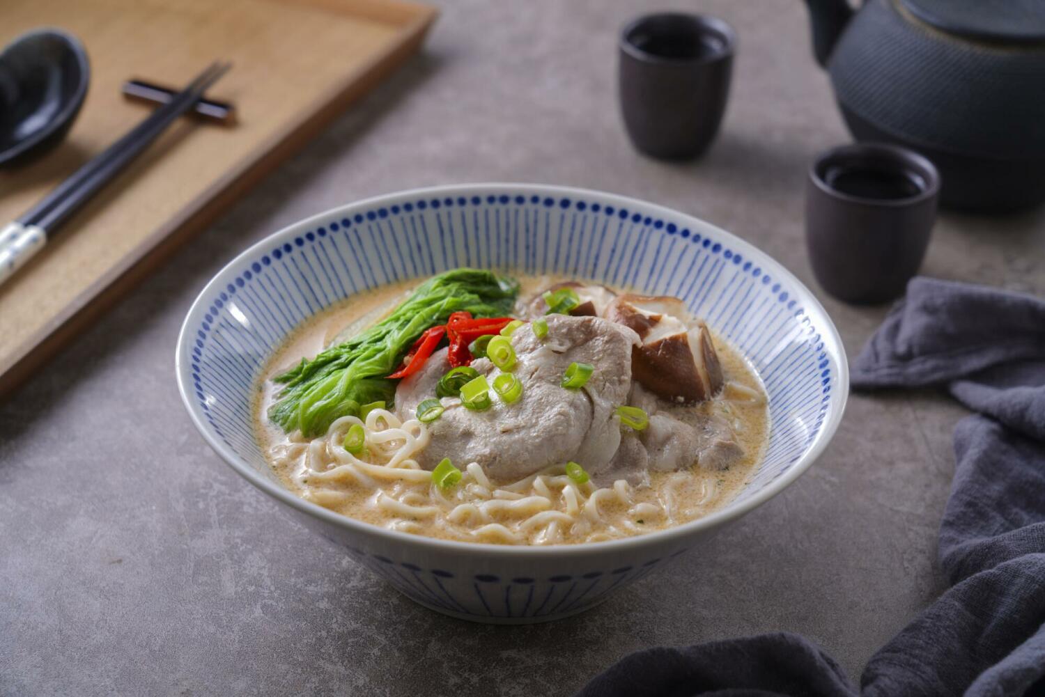 A bowl of Taiwanese-style ramen with noodles in a rich broth, paired with sliced meat and vegetables, showing a stable and elastic noodle texture.