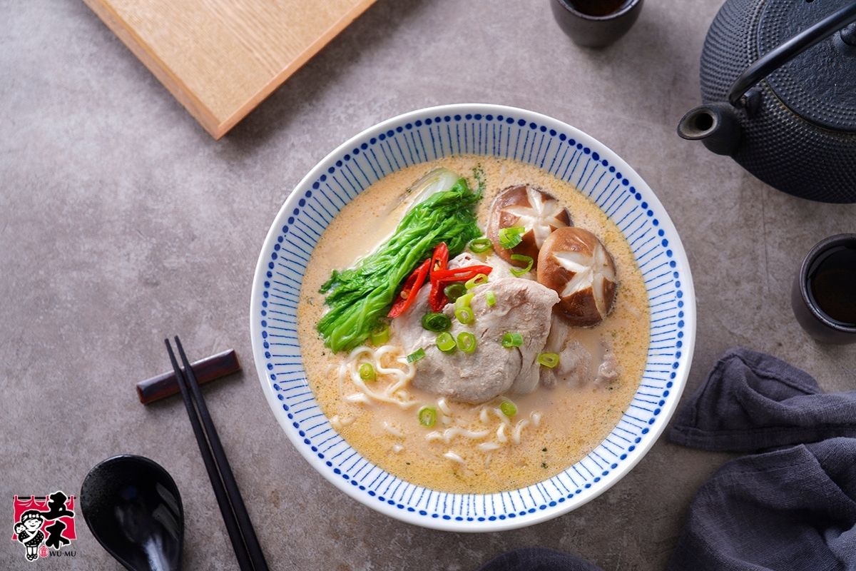 Miso ramen noodle soup with sliced meat, shiitake mushrooms, leafy greens, and chopped scallions.