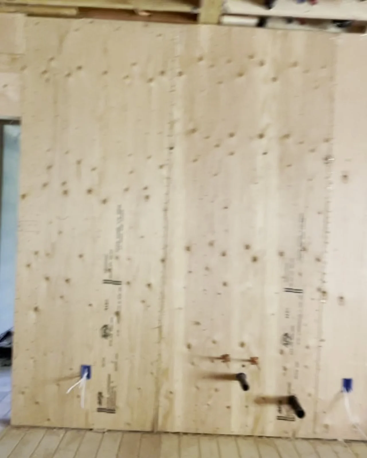 A sheathed wall panel photographed close: fasteners set at tight regular spacing around every panel edge, anchor hardware bolted through at the sill