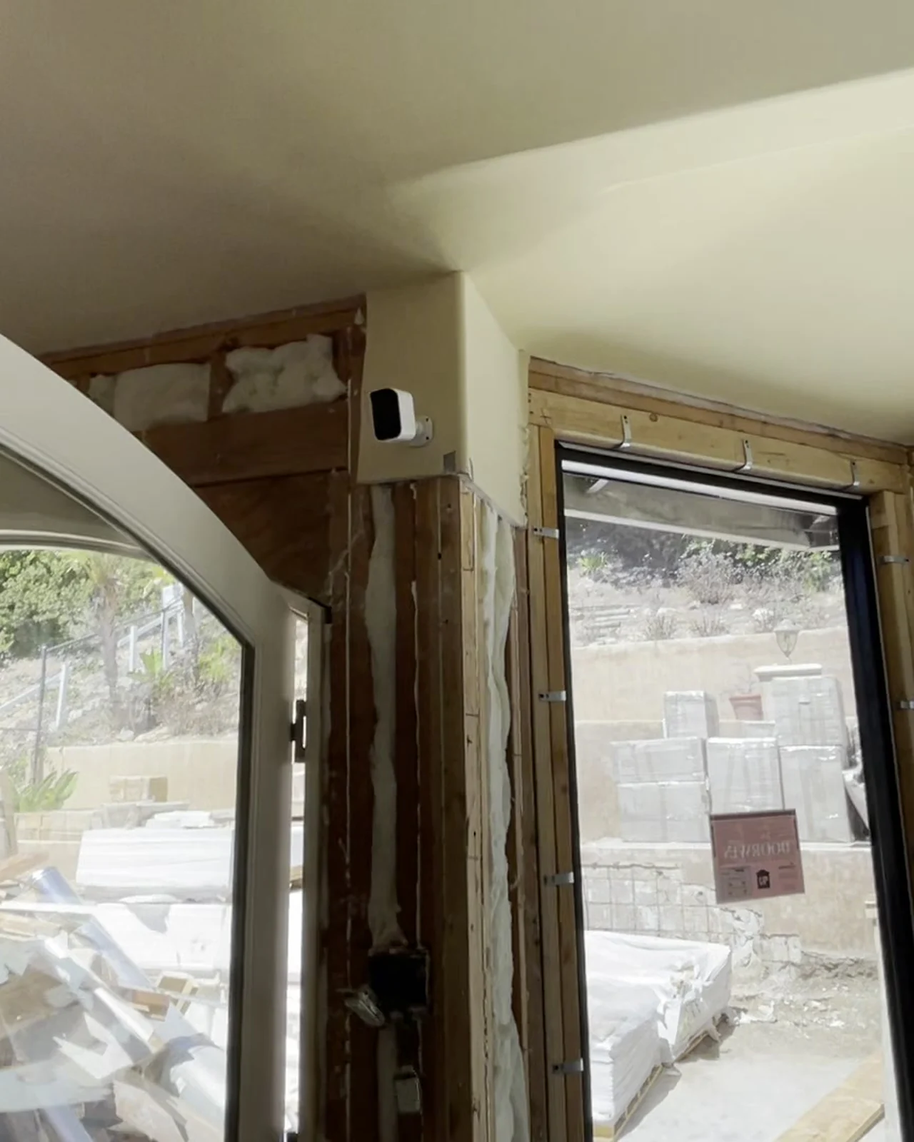 Factory-glazed units propped against the frame ahead of install, the widened openings they belong to visible behind