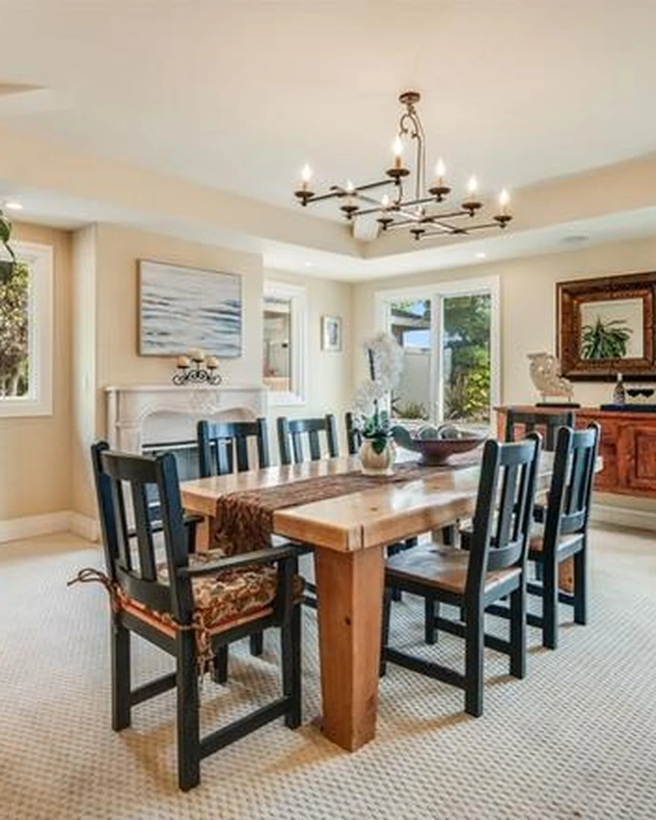 Original dining room with beige walls, a rustic wood table with leather-and-wood chairs, a traditional fireplace, framed art and carpet