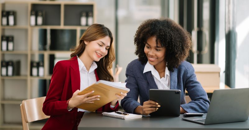 Empresárias conversam em um escritório e analisam dados para implementar o link de contratação online de planos recorrentes.