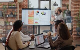 Equipe de negócios em reunião, com um dos colaboradores fazendo apresentação e buscando maneiras de reduzir o churn de clientes.