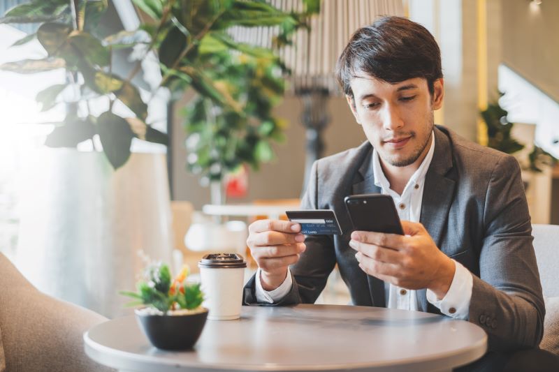 Empresário em um café realiza pagamento do serviço contratado com empresa que fez criteriosa avaliação de plataformas de cobrança recorrente.