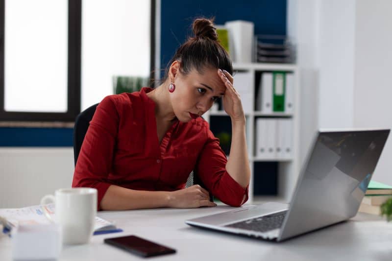 Mulher de negócios em seu escritório olhando confusa para o computador enquanto tenta emitir nota fiscal eletrônica.