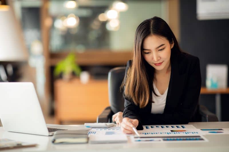 Importância de entender o que é análise de dados representada por empresária no escritório observando gráficos e relatórios.