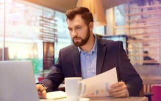 Homem de terno observa tela do notebook, lendo sobre o que é plano de contas.