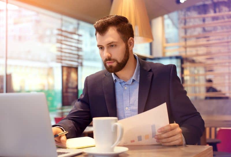 Homem de terno observa tela do notebook, lendo sobre o que é plano de contas.