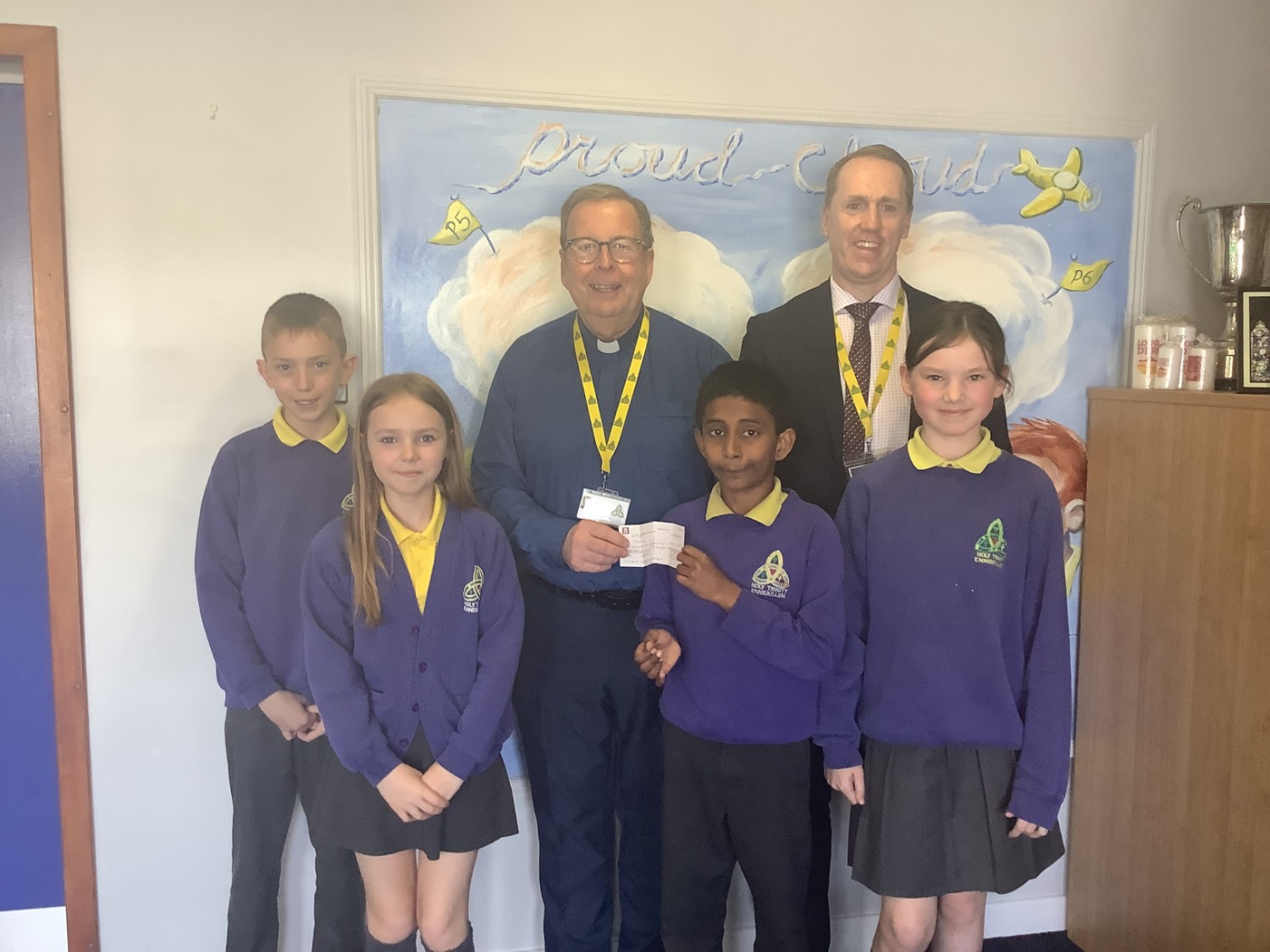 Mr Treacy and some of our KS2 pupils present Deacon Martin with a cheque for Trócaire.  The money was raised by classes accross our school during the run up to Easter.
