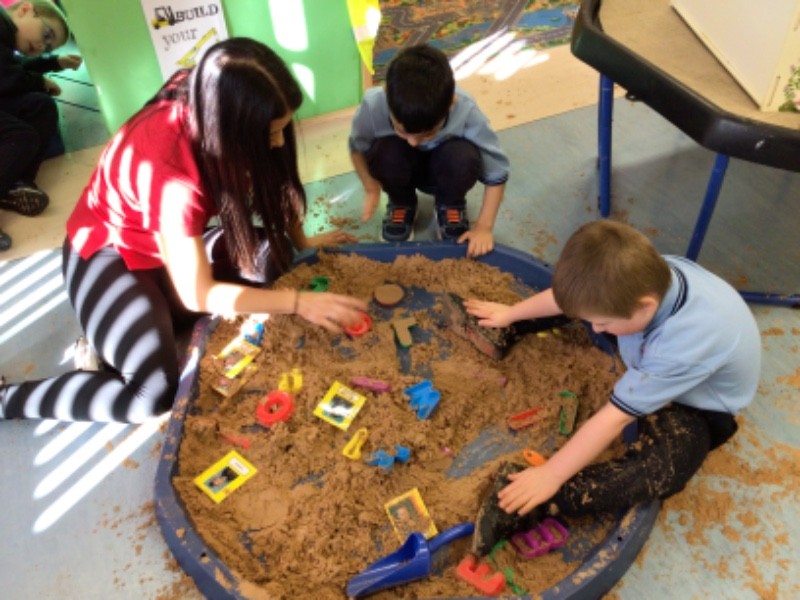 Sharing space and sensory experiences at the sand tray, whilst promoting opportunities in literacy for name and picture recognition.