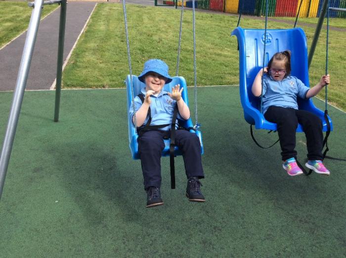 Happy faces getting a go on the swings round the Trim trail.
