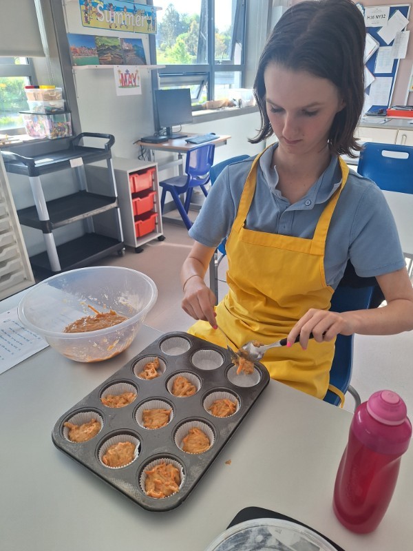 Amy is carefully filling up her muffin cases.