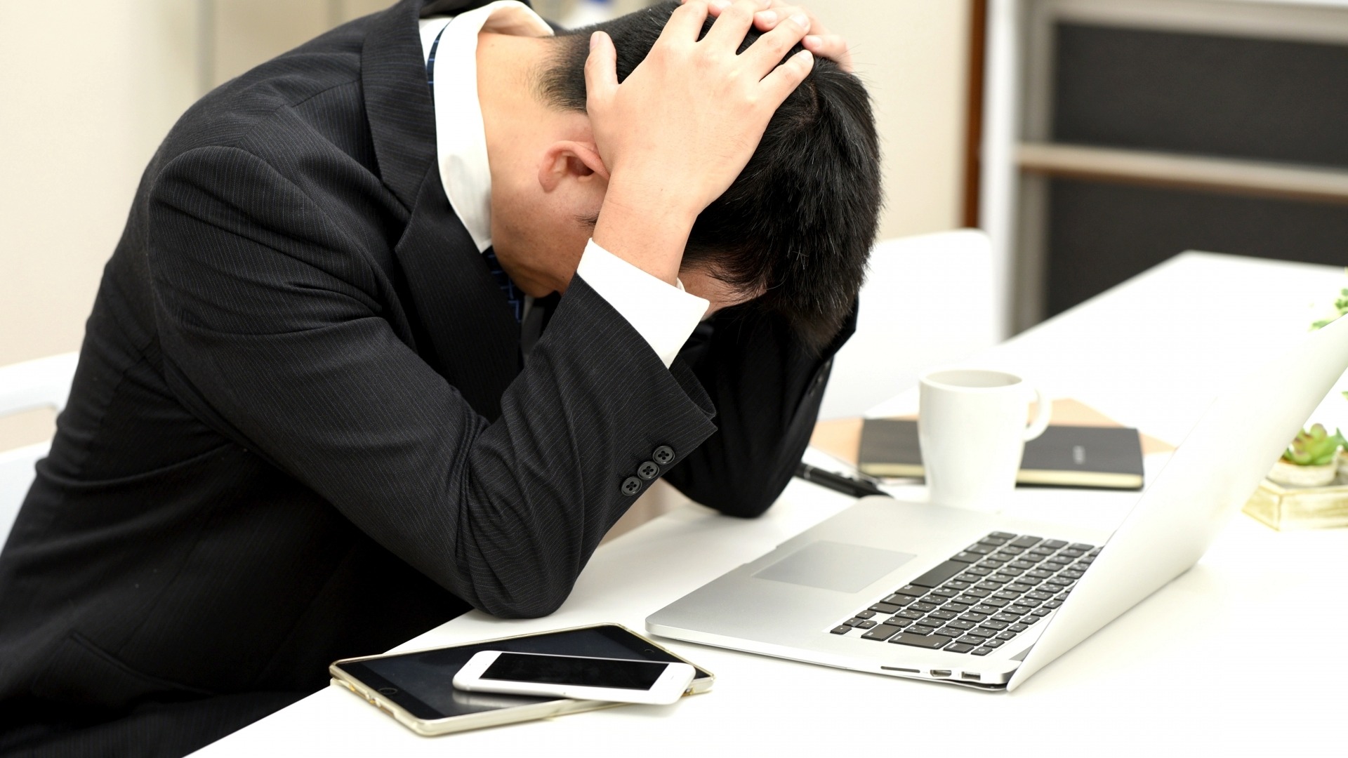 GEO対策や新たなAI検索エンジンへの対応に悩み、ノートパソコンの前で頭を抱えるビジネスパーソン