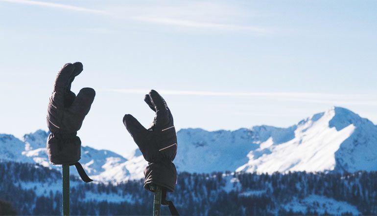 ski gloves on ski poles in front of mountain