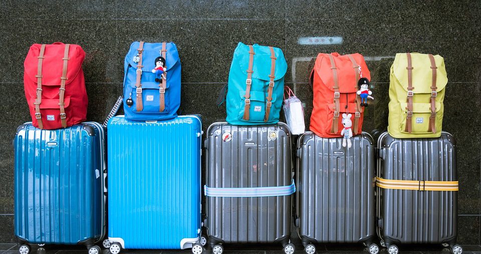 five suitcases and backpacks packed for family ski trip