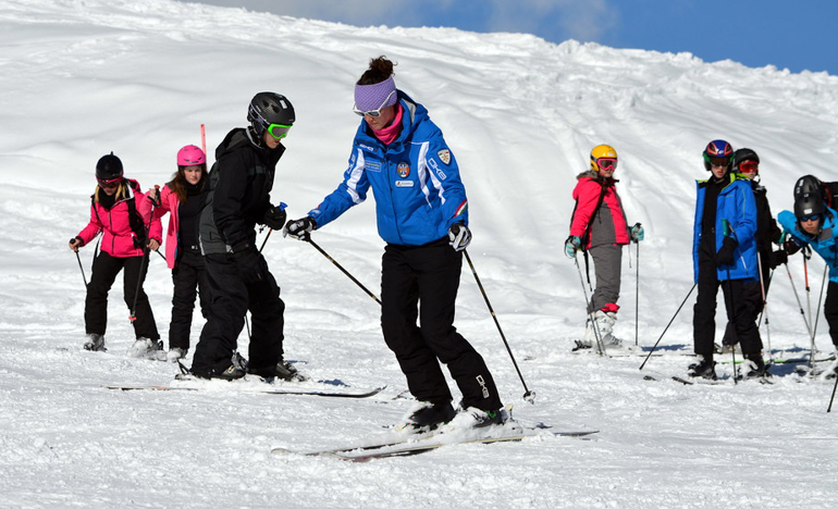 female ski instructor teaches group ski lesson