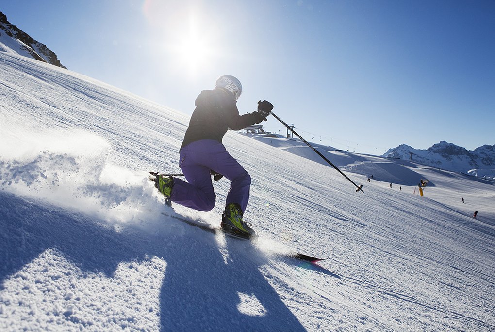 backlit shot of man telemark skiing in the sun