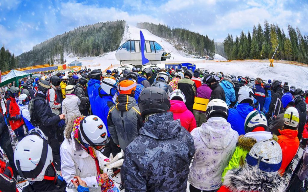 many people in colourful clothing in long line ups for the chairlift