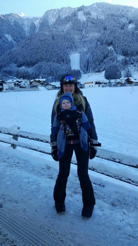 Woman with baby on chest in snowy mountain scenery