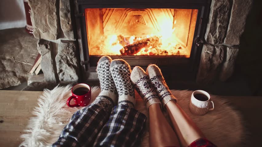 man and woman heat feet by fireplace