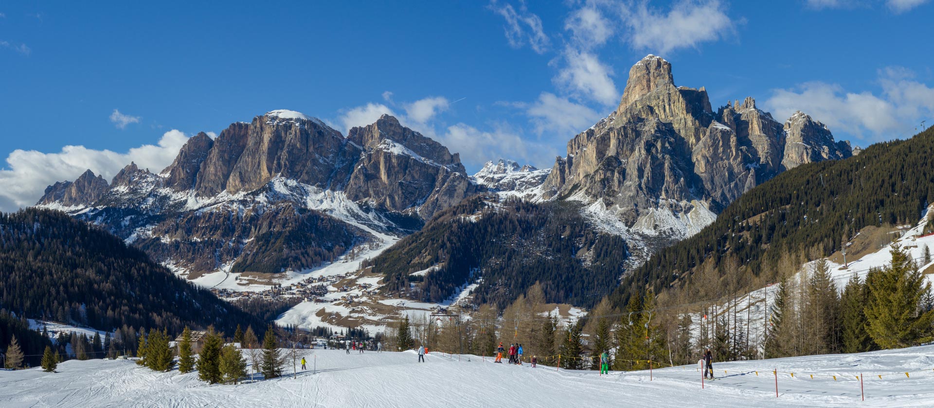 Beginner skiers enjoy a gentle piste in the aki area of Corvara as majestic peaks rise up in the distance