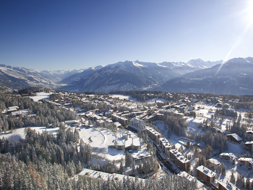 The alpine village of crans montana, nestled between mountains under a sunny sky