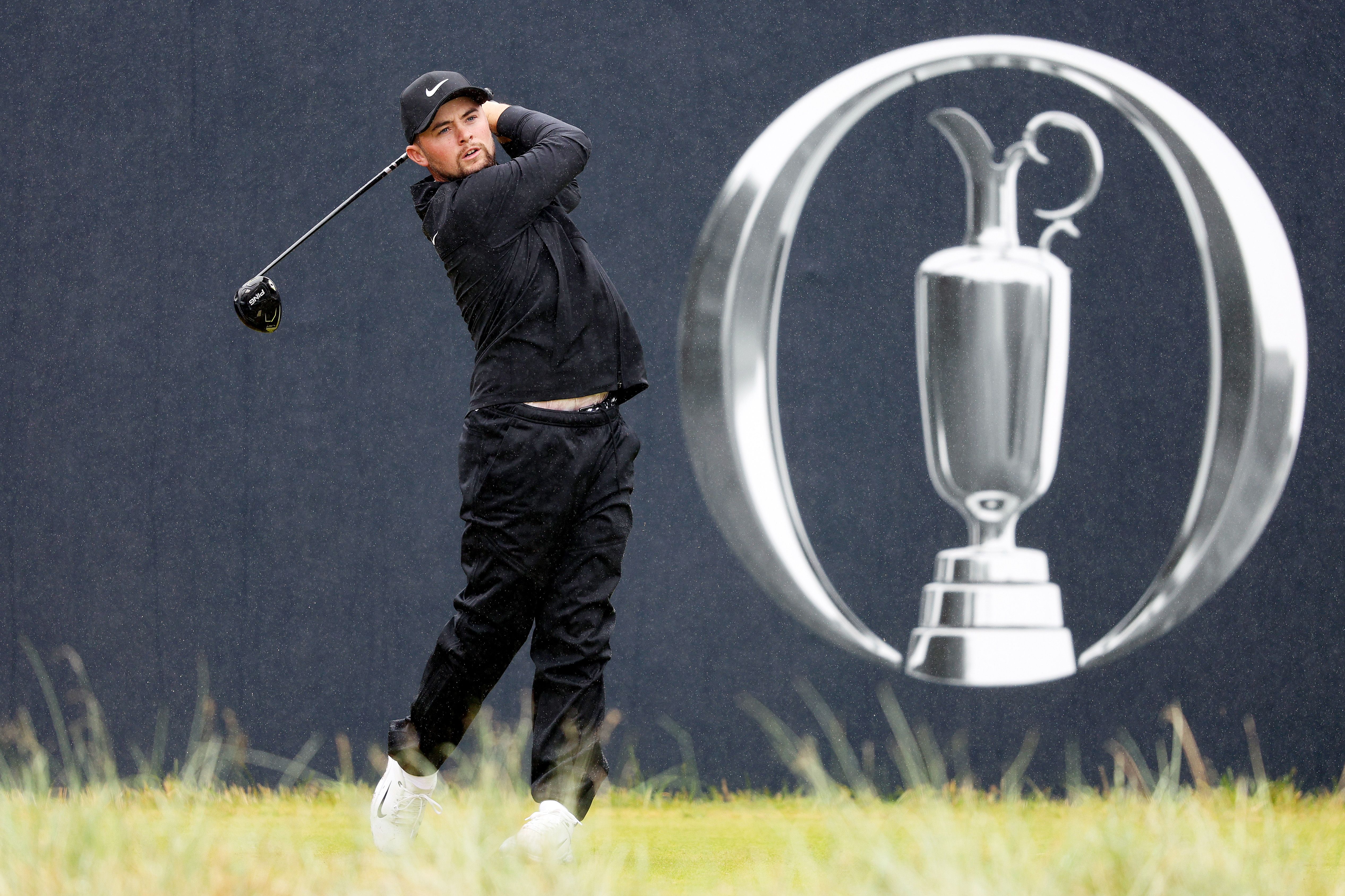 Golfer takes a powerful swing, with The Open Championship Claret Jug logo overlaid.