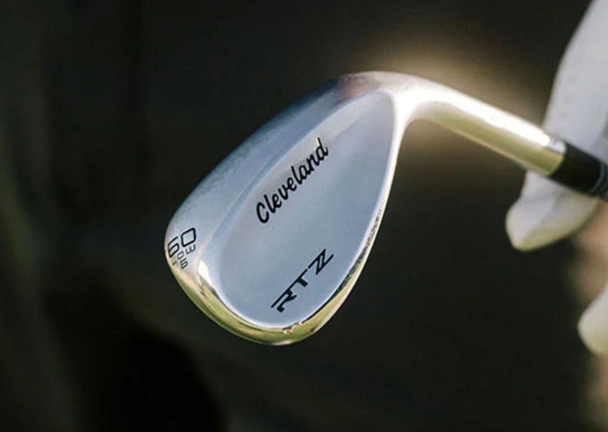 Silver Cleveland RTX ZIPCORE golf wedge held by a gloved hand on a dark background.