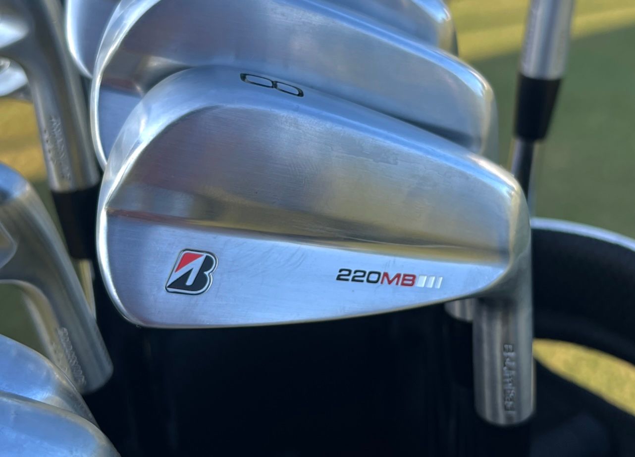 Close-up of several Bridgestone B-Series golf iron club heads in a golf bag.
