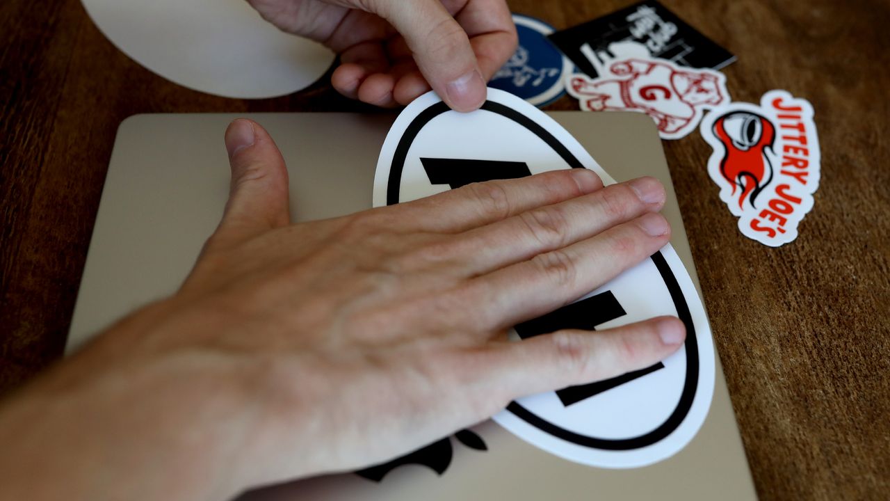 firmly sticking your sticker to the laptop