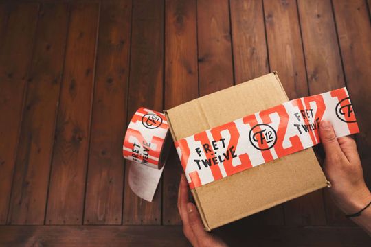 White and orange retro design packaging tape on a brown kraft box.