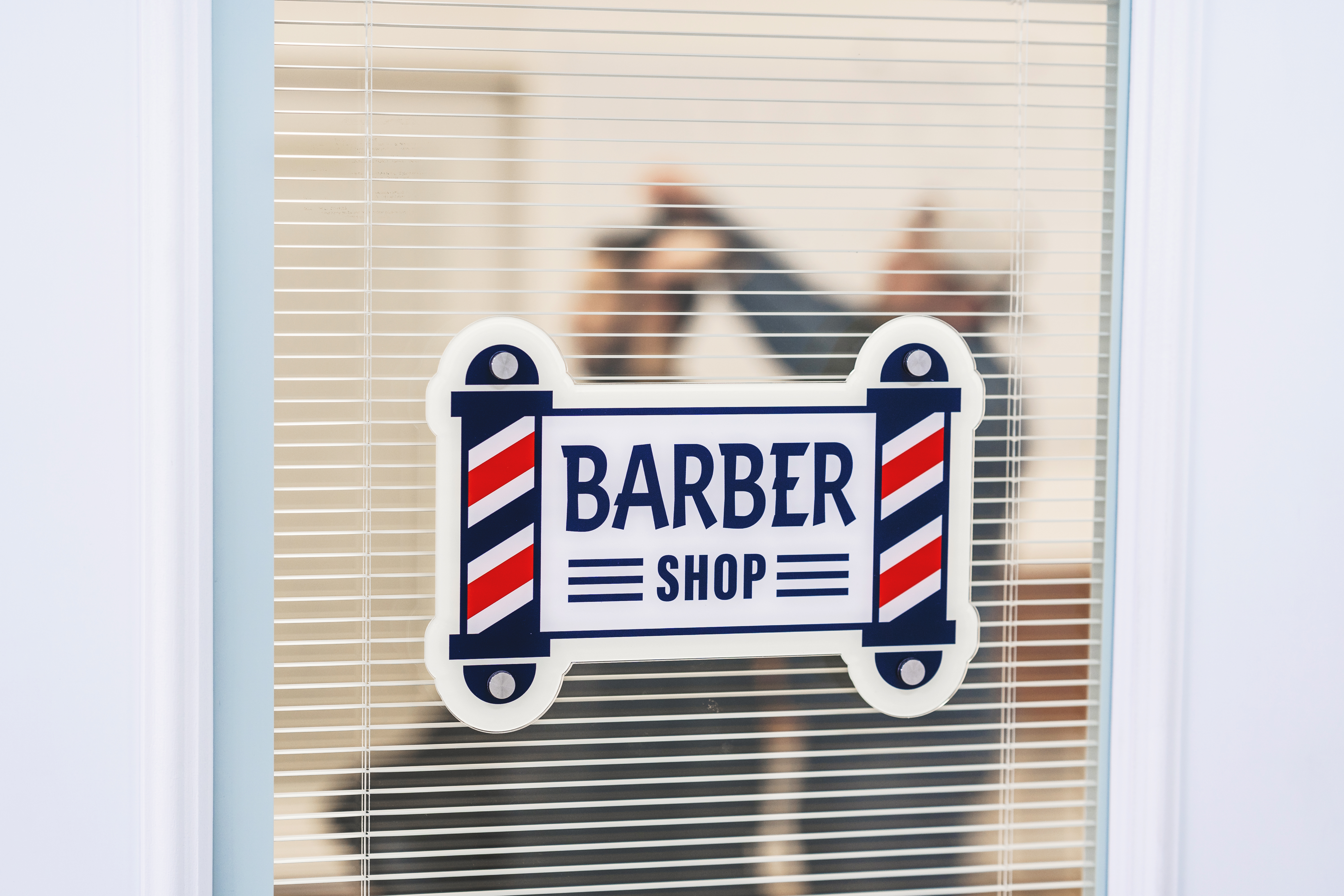 konturgeschnittenes Acrylschild mit der Aufschrift "Barber Shop" in der Form von zwei Barbershop-Stangen