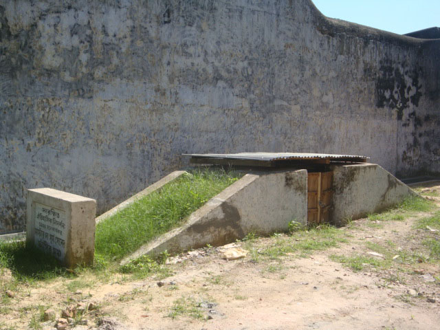 Outdoor stone platform inside a wall, with a memorial tablet