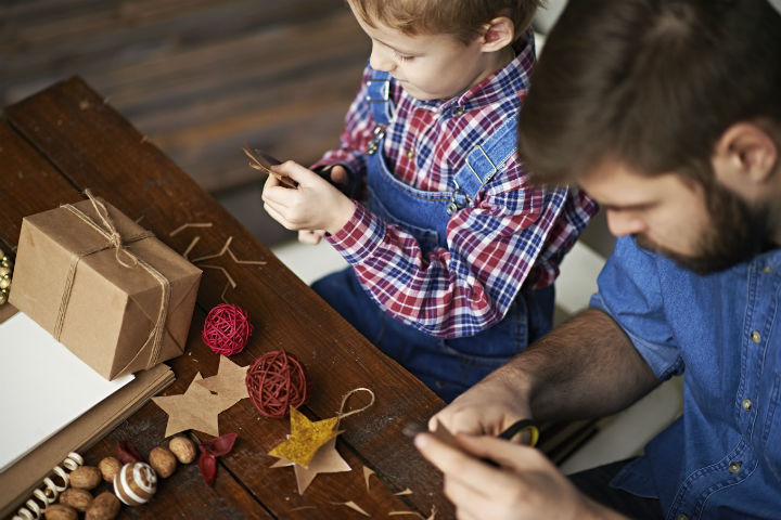 décoration de Noël à faire soi-même. Un papa et un petit garçon préparent des décorations de Noël en papier kraft.