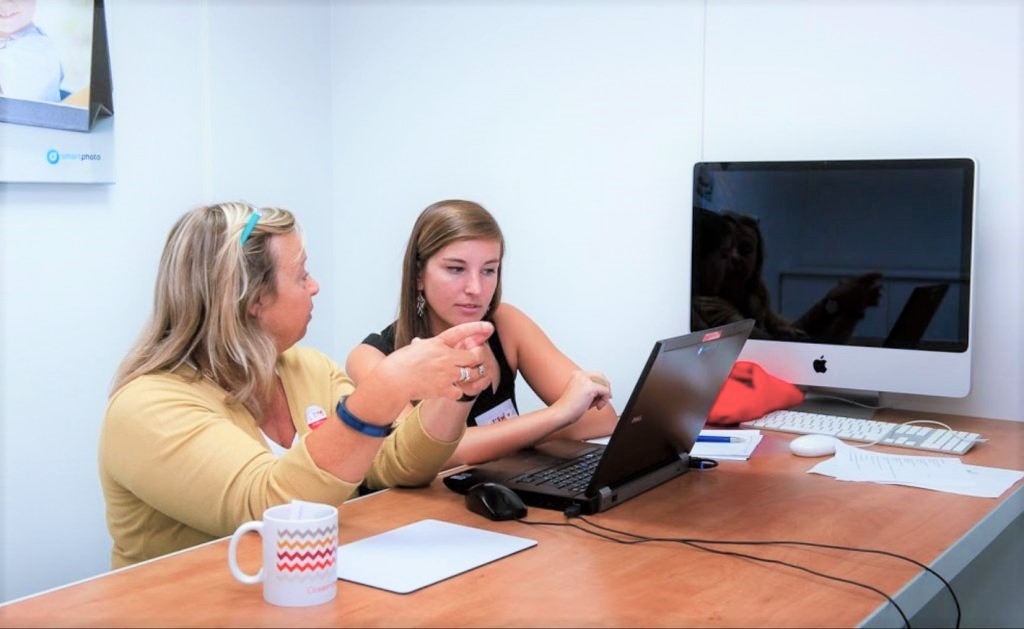 Dialogue avec les client smartphoto - discussion entre deux personnes devant un ordinateur