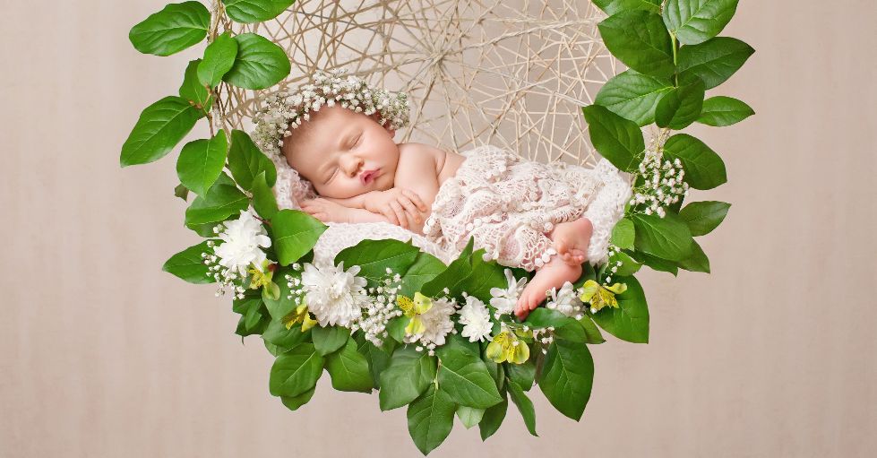 Photos de bébé professionnelles: un nouveau-né endormi est couché dans une couronne de feuilles et fleurs.