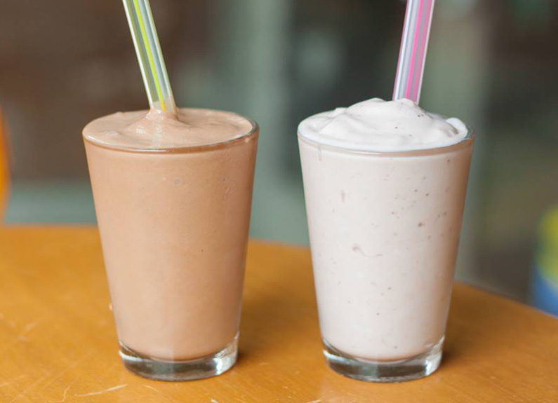 two milkshakes, one chocolate and one vanilla, in glasses with colorful straws