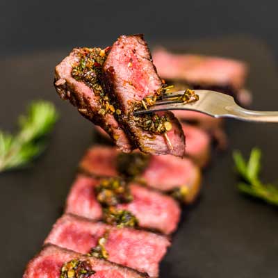 slices of steak with chimichurri drizzled on top