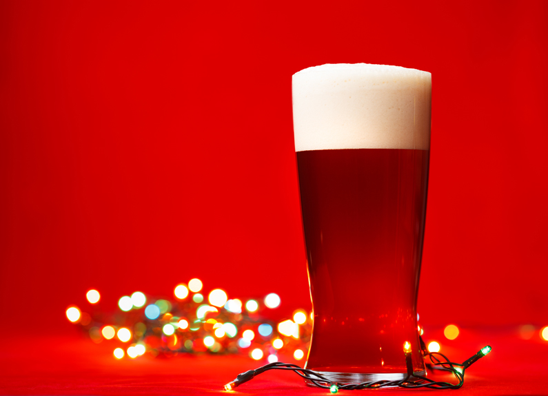 a glass of beer with christmas lights in the background 