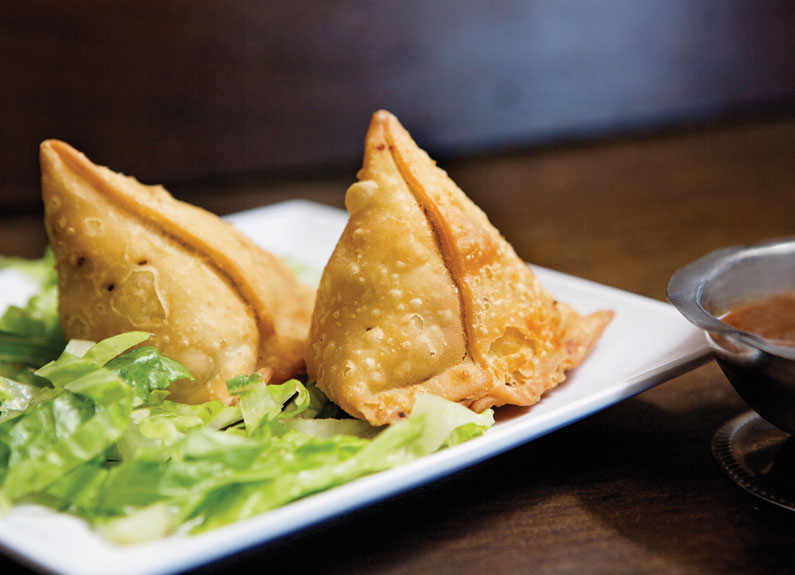 two samosas on a plate with lettuce