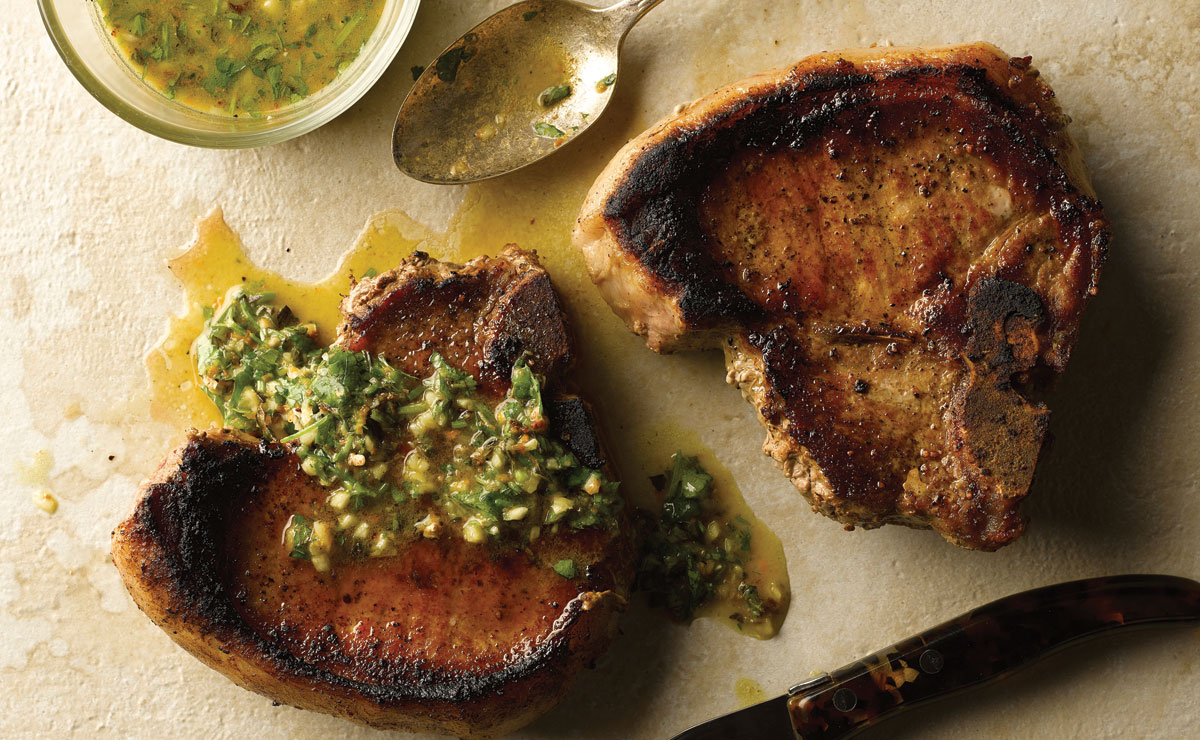 two pork chops covered in mojo sauce