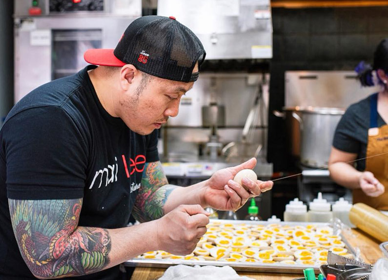 nudo house co-owner qui tran cuts ramen eggs