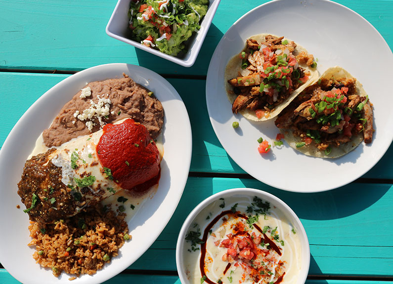 four dishes of mexican food on a blue table