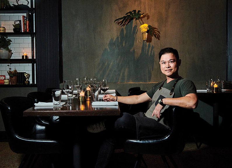 a smiling man sitting at a bar