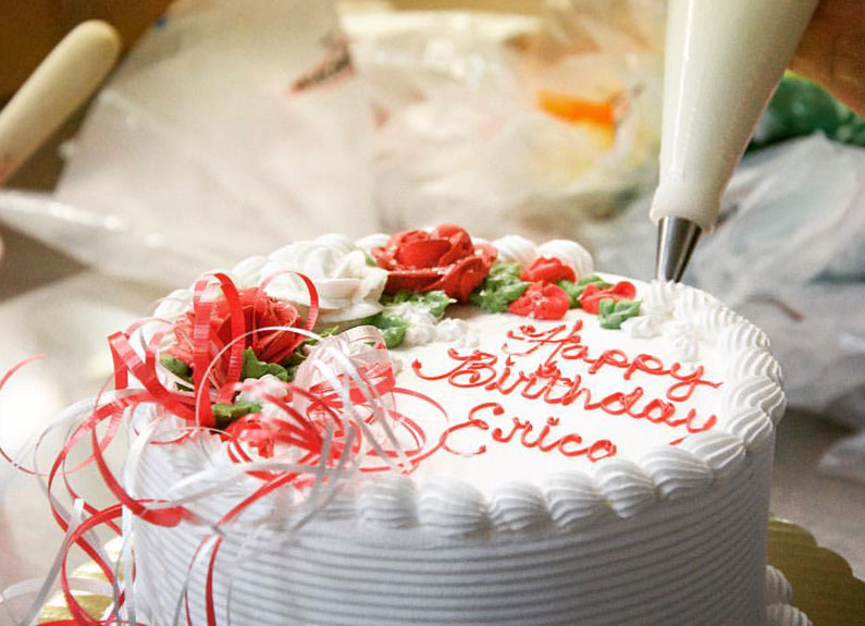 a round birthday cake with white icing and red lettering