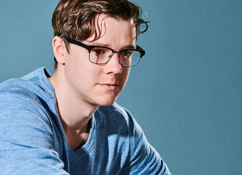 a young man with glasses in front of a blue background