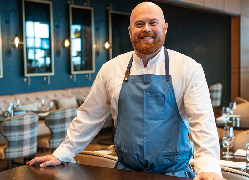 a smiling chef with a blue apron