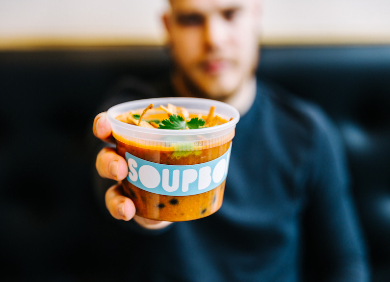 a man holding a cup of soup