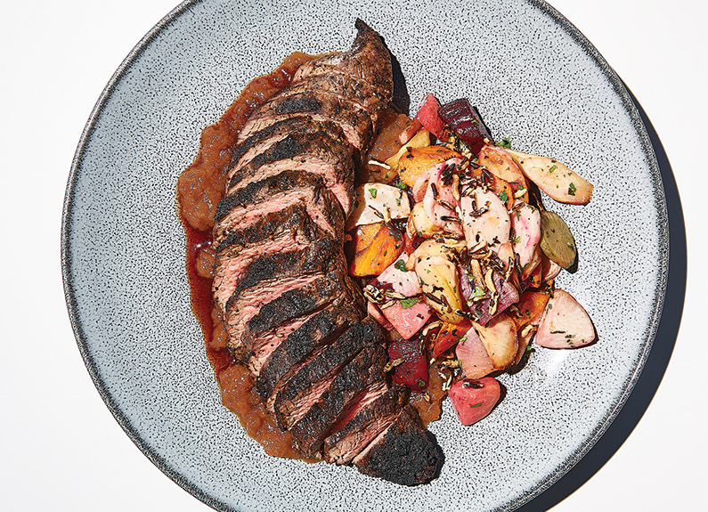 a sliced steak on a plate with roasted vegetables